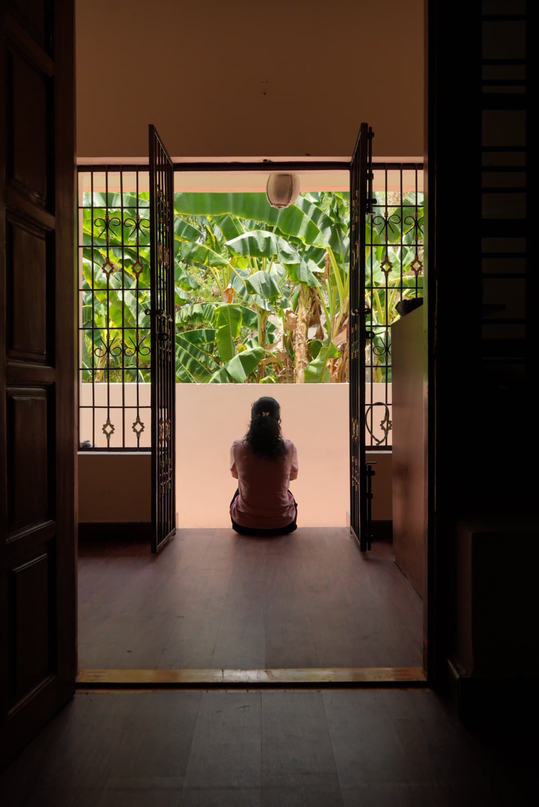 A guest sitting in the balcony doorway, framed by green trees
