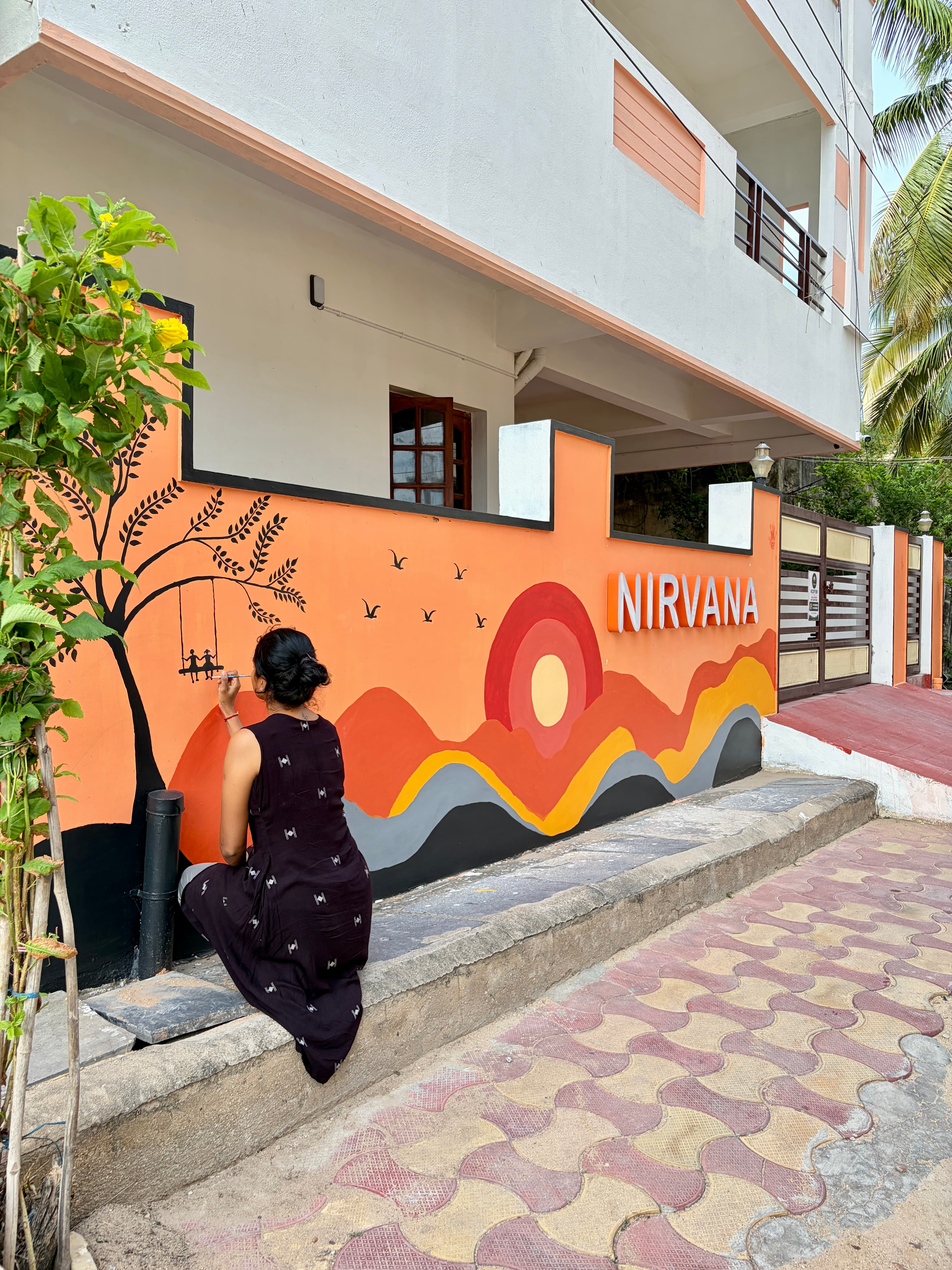 Painting the orange sunset mural on the front wall of Nirvana Backpackers