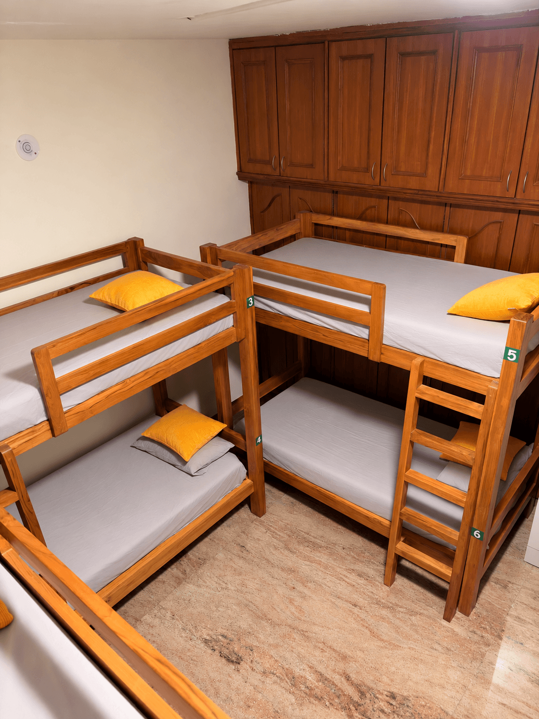 Wooden bunk beds with yellow pillows and wooden lockers above